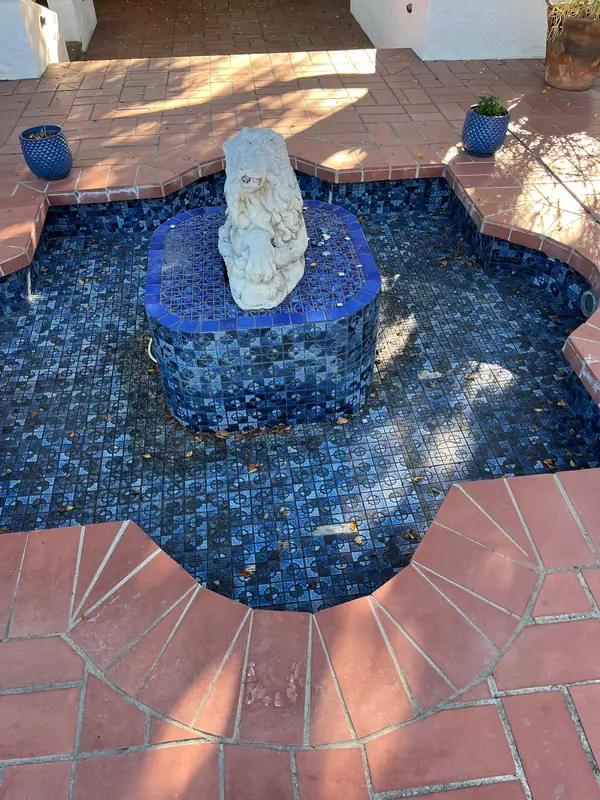 Before: the fountain in dark navy mosaic, with worn brick around it