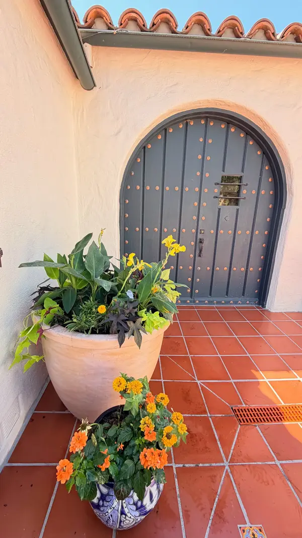 New pots by an arched door, on restored terracotta tile