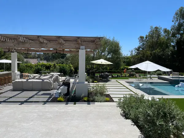 A pool terrace mid-install, with turf between the pavers