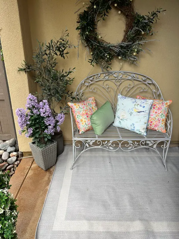 Potted flowers and an olive by a porch bench