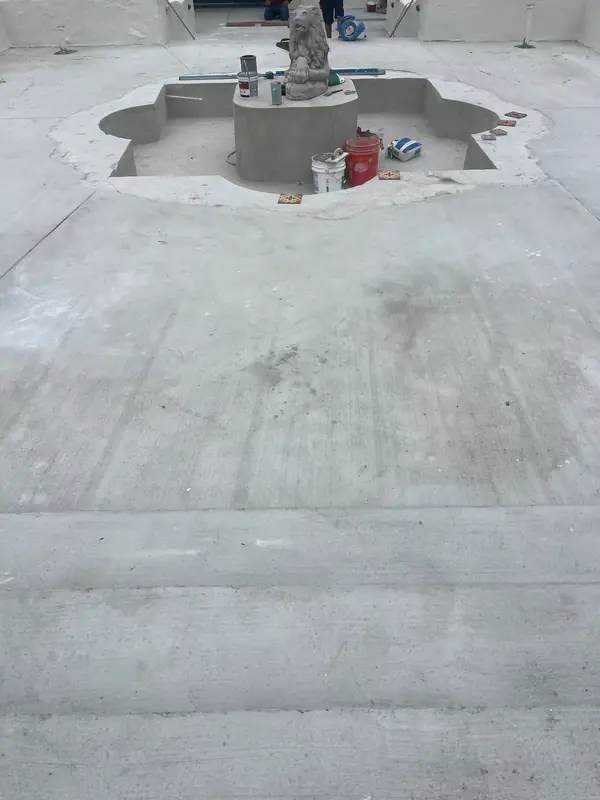 A new concrete base, ready for tile, around the stripped fountain