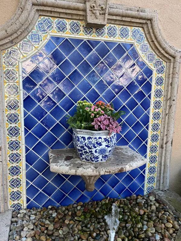 A blue and white pot set into a tiled wall fountain